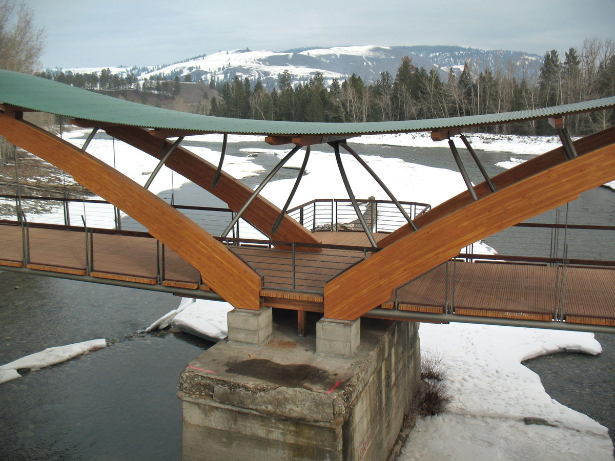 Outdoor overcast snowy image of Princeton Bridge of Dreams showing large glue-laminated timber (glulam) arches and wooden decking