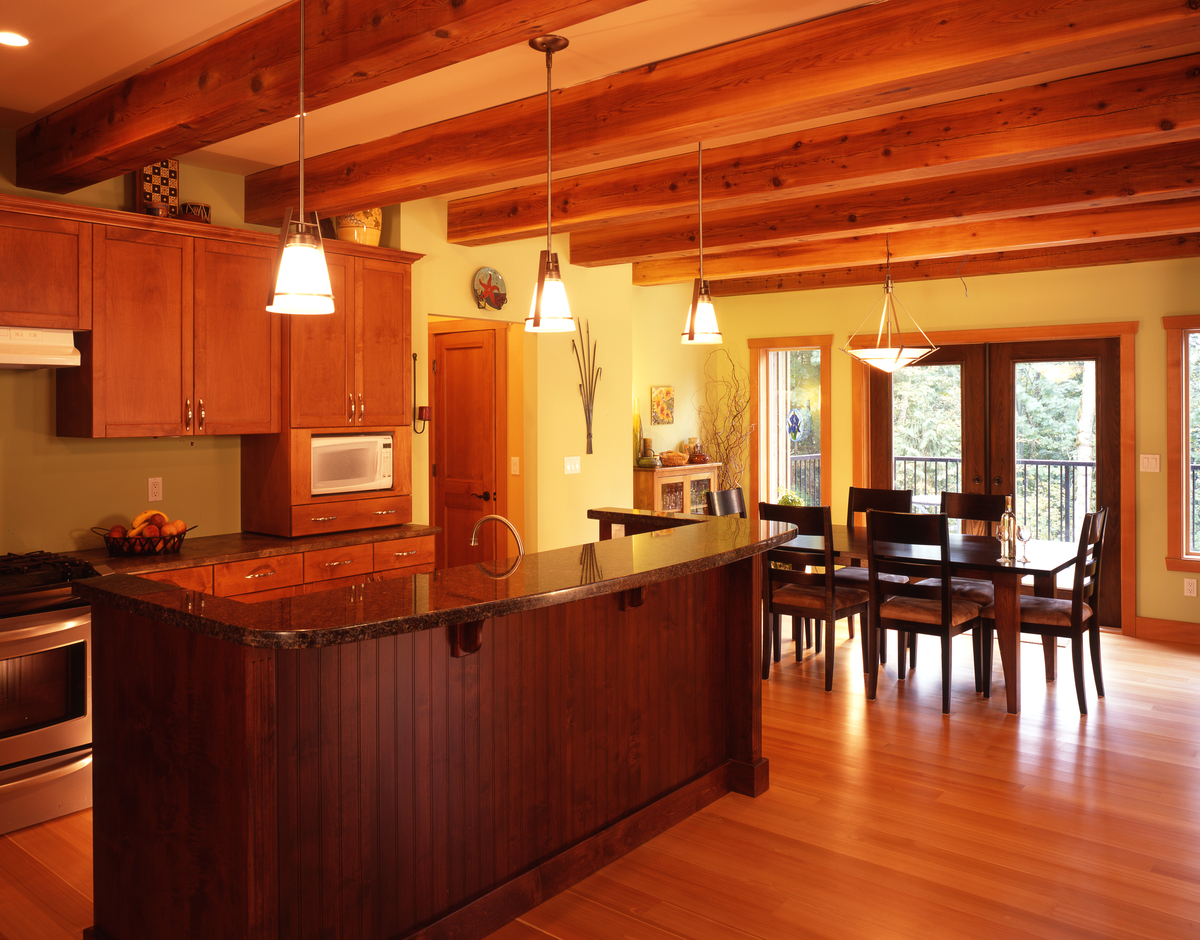 Daytime interior image of kitchen and dining area with extensive use of wood for cabinets, counters, flooring, and ceiling beams - used as Western Larch (Larix occidentalis) usage examples