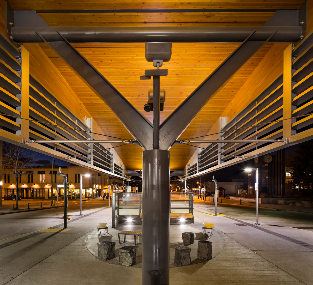Nighttime outdoor close up view of steel column which supports 60-metre-long curvilinear roof span is achieved through the use of two engineered glue-laminated timber (glulam) beams supporting nine-metre-wide decking panels