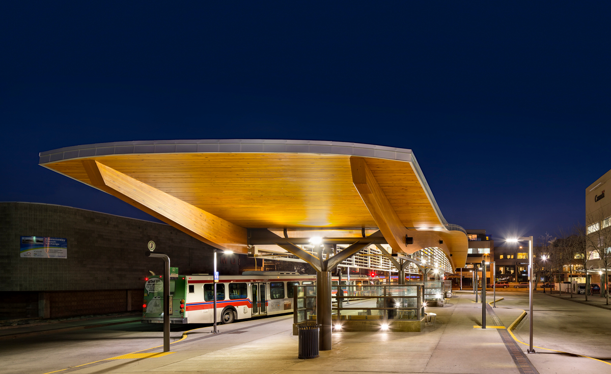Nighttime view of Queensway Transit Exchange showing Impressive 60-metre-long curvilinear roof span which was achieved through the use of two engineered glue-laminated timber (glulam) beams supporting nine-metre-wide decking panels.