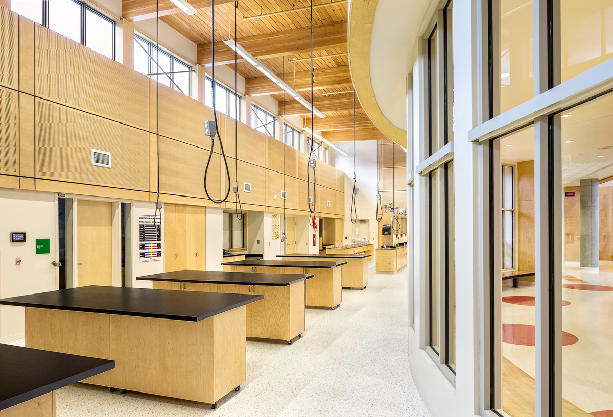 Interior daytime image showing the mass timber ceiling of the Southern Okanagan Secondary School three storey science lab, including glue-laminated timber roof beams, wood paneling, wooden trim, and wooden workstation tables