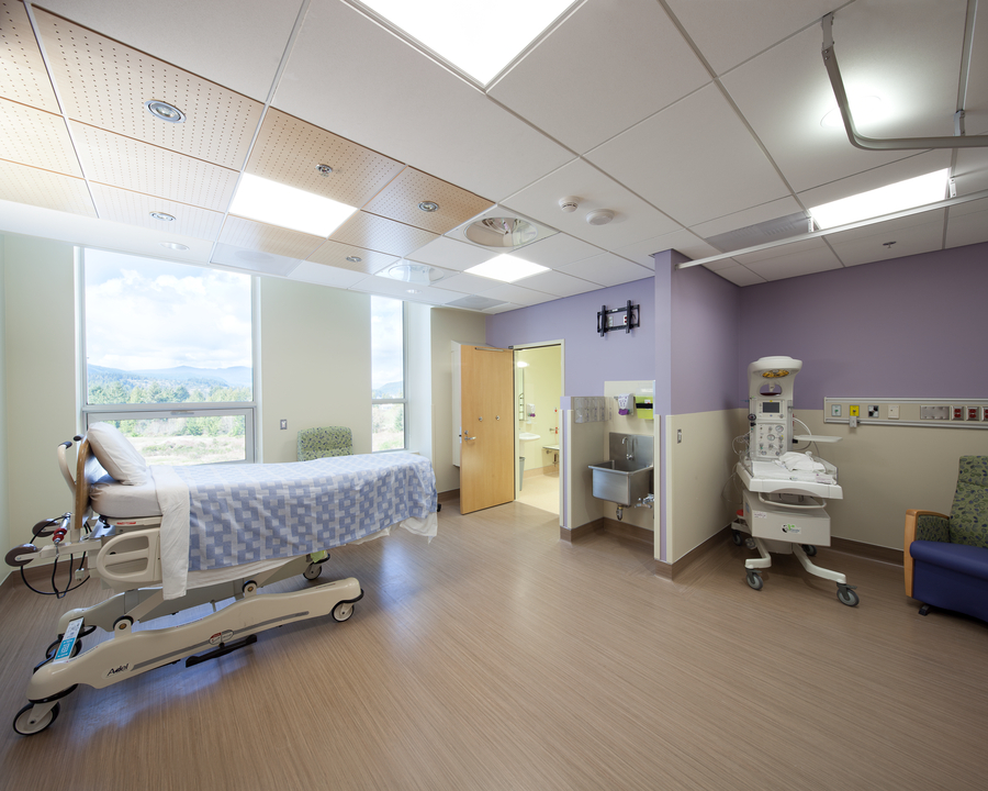Interior of hospital room with hospital beds and newborn beds shown with some wooden acoustic tiles