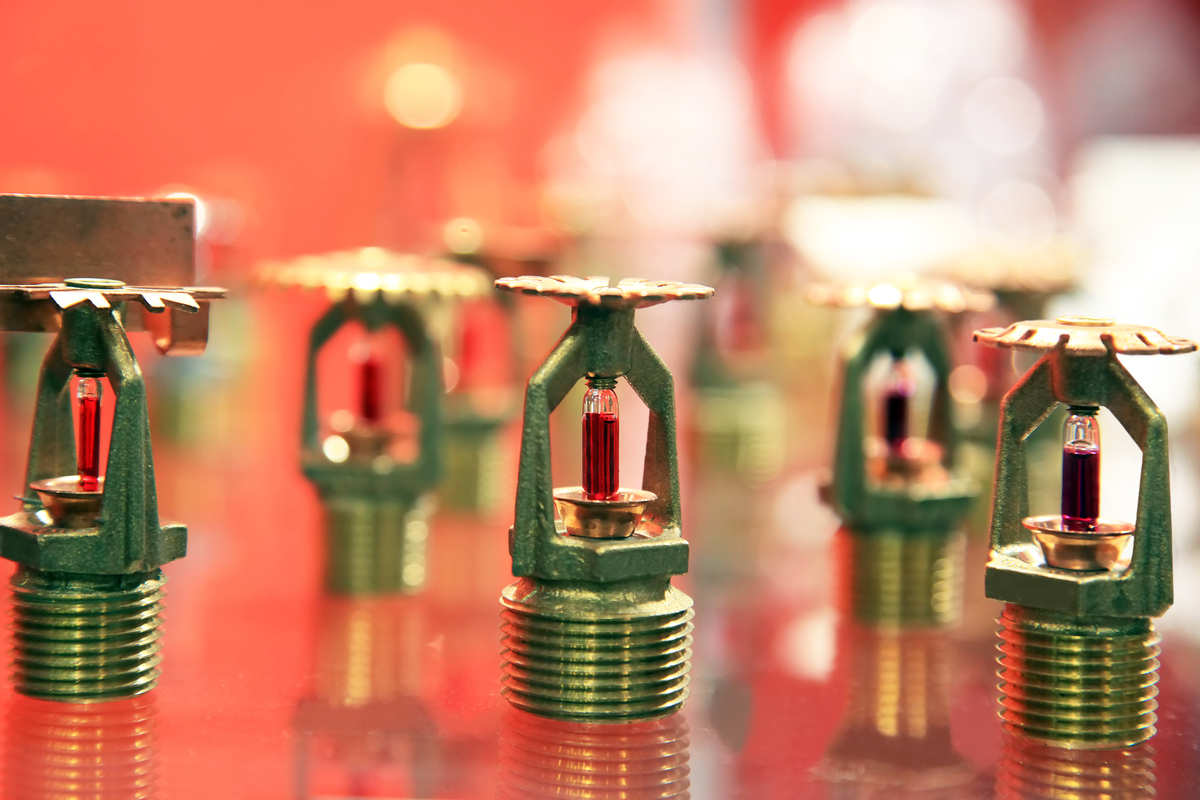 Close up view of fire suppression sprinkler heads showing brass heads with integrated glass fuses filled with red alcohol