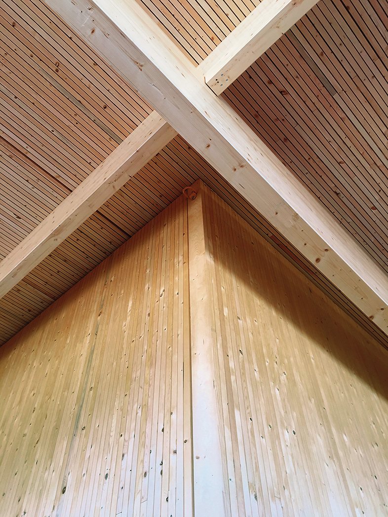 Interior close up view of glue-laminated timber (glulam) columns and beams, tall wood walls, and wood roof panels as shown within StructureCraft Manufacturing Facility