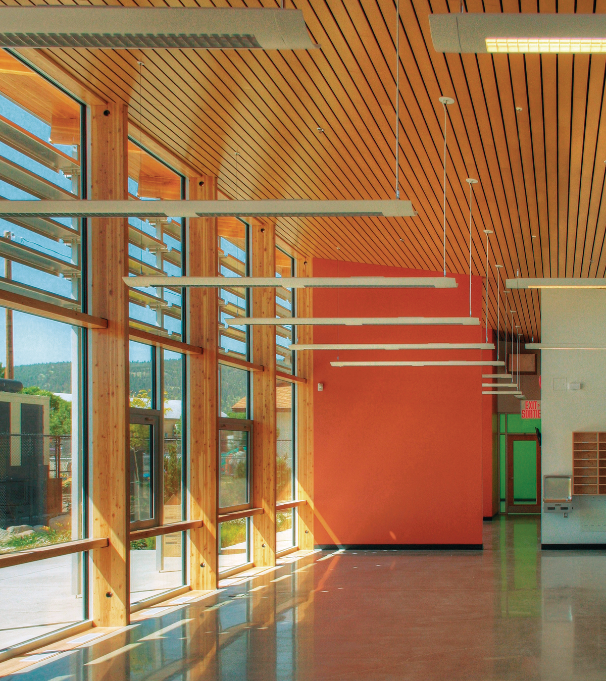 Interior sunny daytime view highlighting use of vertical mass timber columns along with wood trim and decorative dimensional lumber ceiling inside newly completed Summerland RCMP Detachment