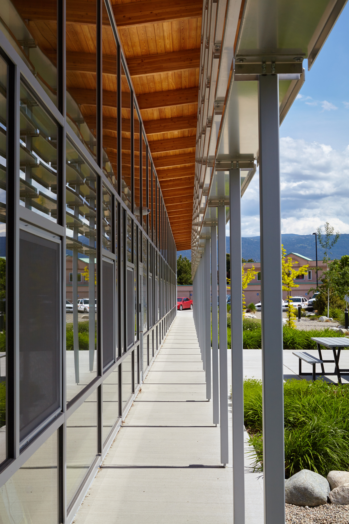 Exterior daytime view of Summerland RCMP Detachment highlighting glue-laminated timber (Glulam) beams supporting exterior soffits clad with unfinished pine planks