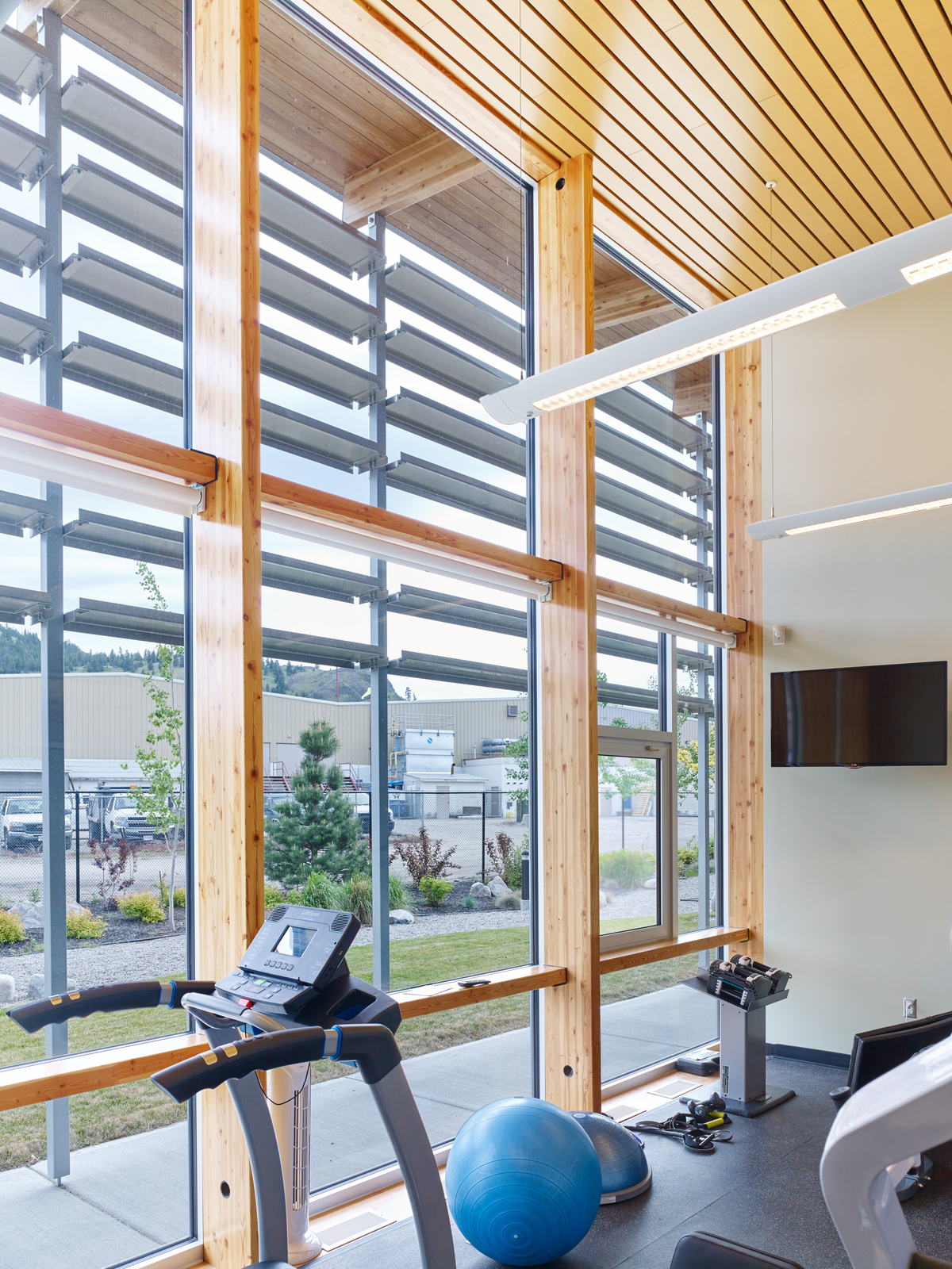 Interior sunny daytime view highlighting use of vertical mass timber columns and decorative dimensional lumber ceiling inside Summerland RCMP Detachment exercise room