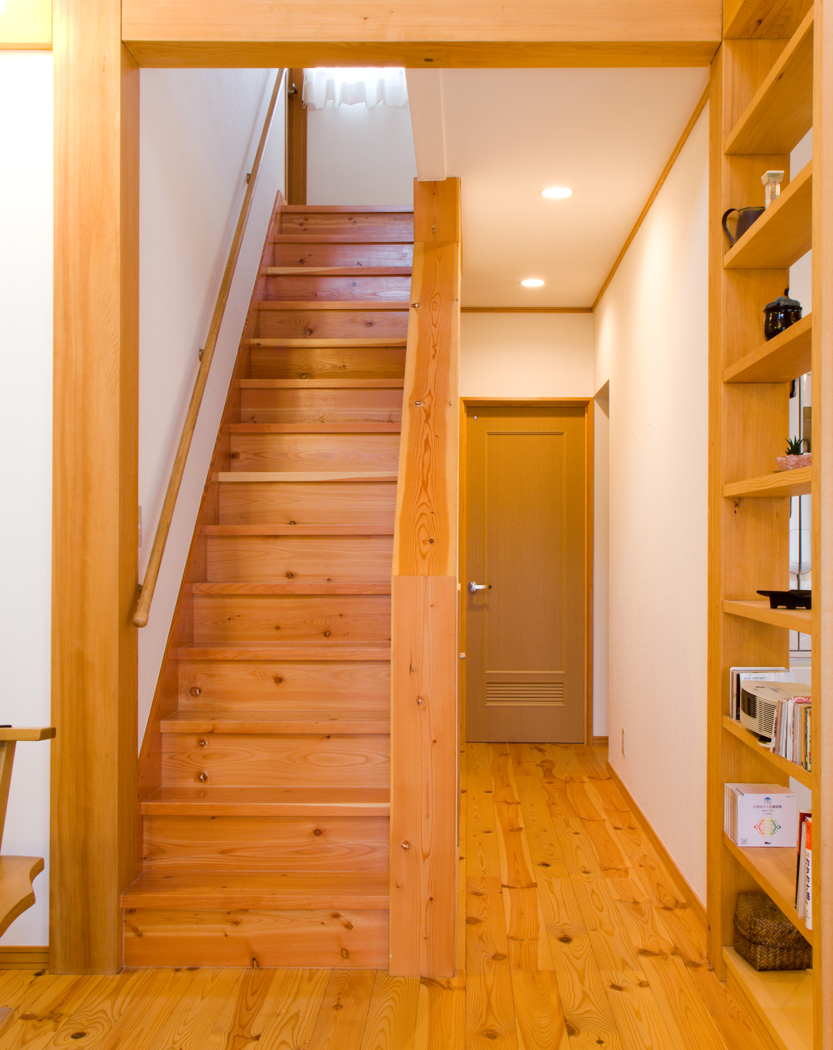 Interior daytime image of Suzuki House, showing extensive use of Ponderosa Pine (Pinus ponderosa) wood flooring, trim, stairway, and bookshelves