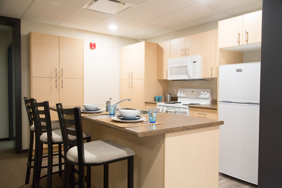 Interior welcoming image of Trinity Western University Jacobson Hall dwelling unit kitchen showing wooden trim and wooden cabinets