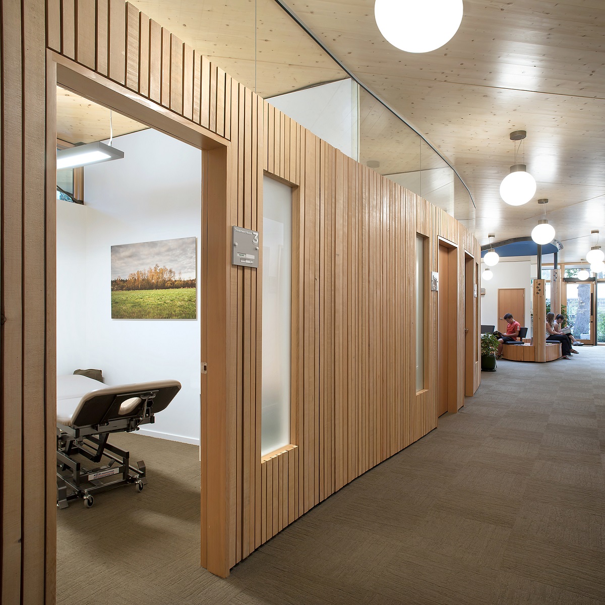Interior daytime image highlighting extensive use of natural wood, including trim, wall panels, columns, and roof constructed from cross-laminated timber (CLT) panels within the Tall Tree Integrated Health Centre