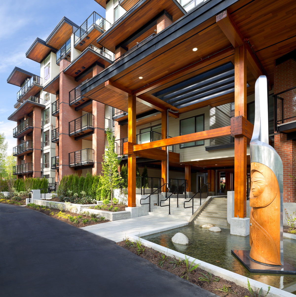 Exterior daytime view of multi-storey post & beam main entrance of 'The Shore', a multi-building residential development with many large wooden decks and balconies