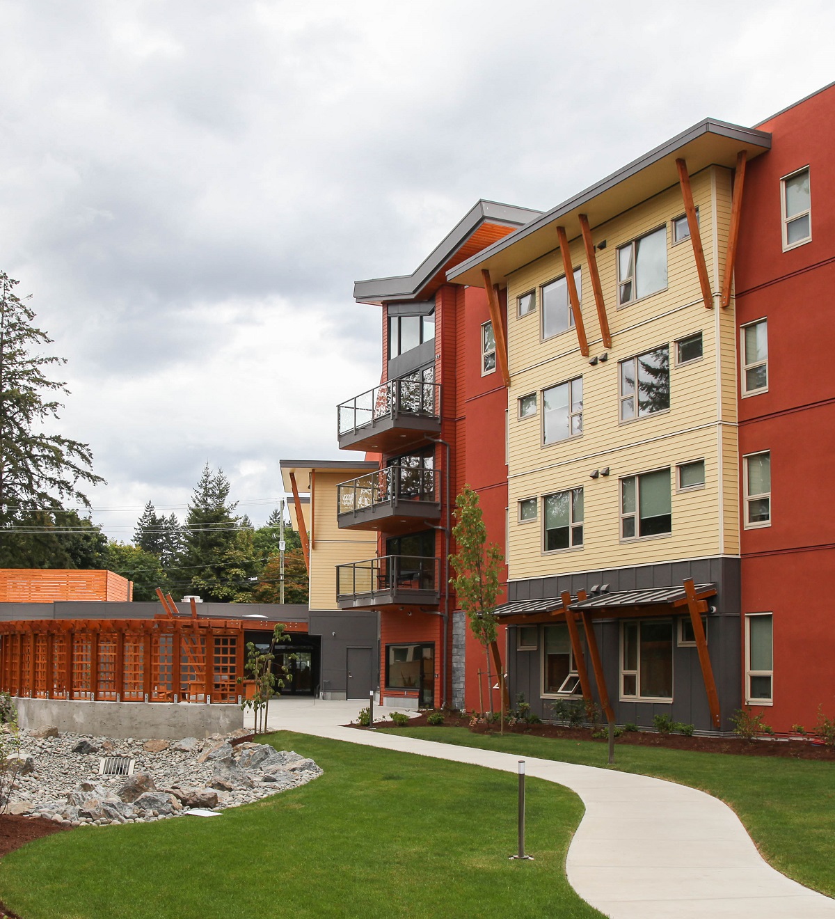 Exterior daytime view of four-storey light frame low rise Ts'i'ts'uwatul' Lelum Assisted Living Facility showing rear of building and highlighting wood use for lumber, millwork, plywood, Douglas-fir struts and soffits, and trim