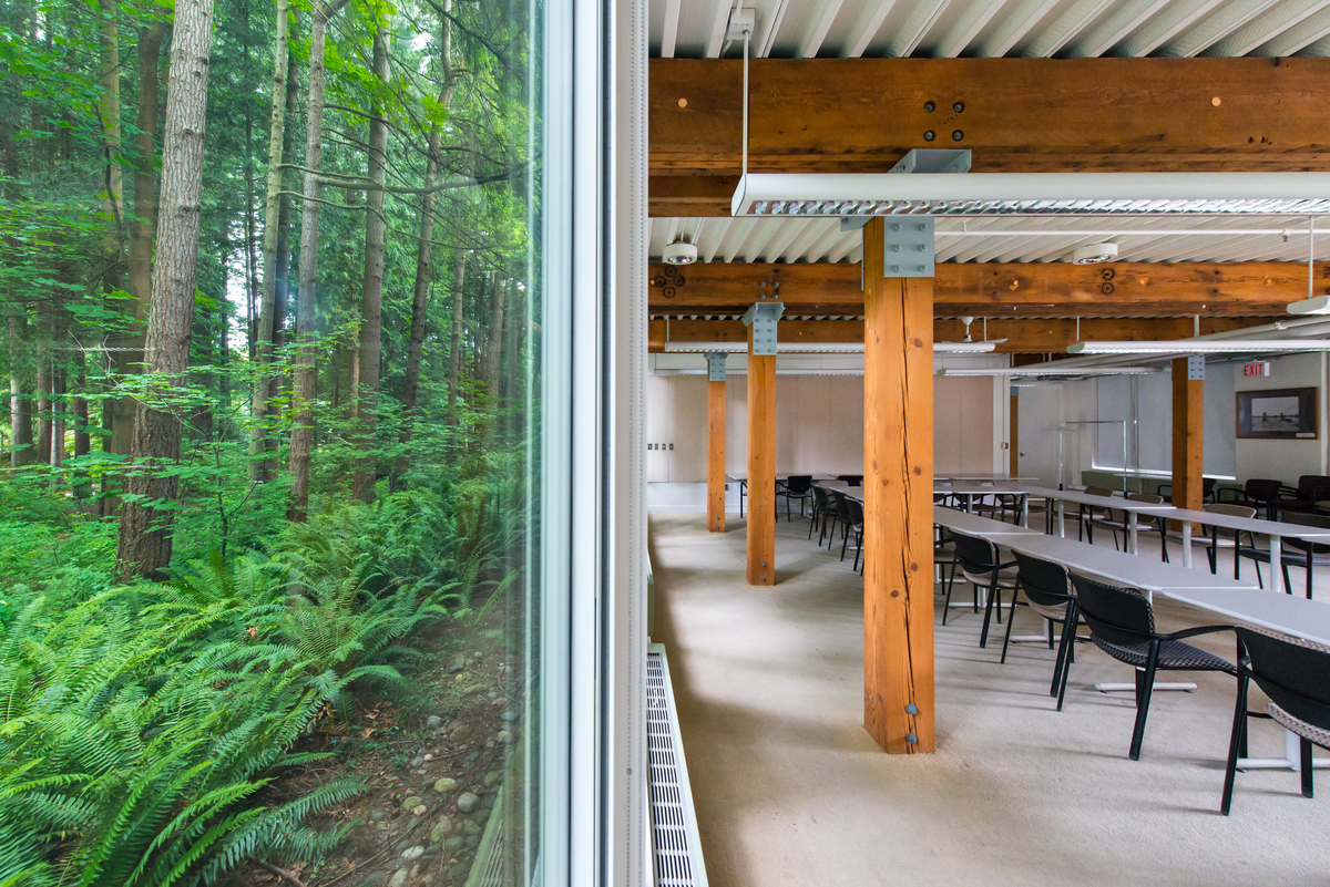 solid-sawn heavy timber beams and columns, with associated metal mating plates, and shown in this ground floor image at the UBC CK Choi Building assembly room with glazed exterior