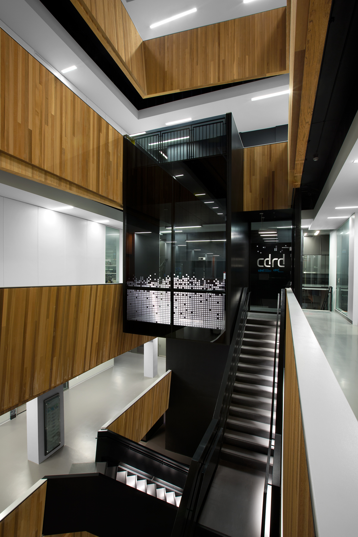Multi storey stairwell interior image showing prominent use of exposed wood throughout the building, including wall cladding in the atriums, exposed wall guard protection and trim