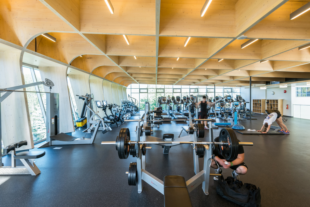 Interior daytime view of two-storey UBCO Fitness & Wellness Centre populated exercise room, highlighting cross-laminated timber (CLT) and glue-laminated timber (Glulam) elements