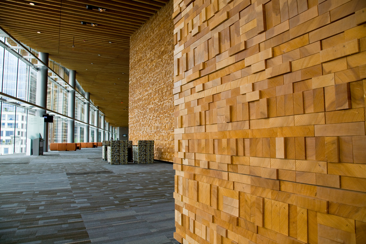 Sunny interior view of Vancouver Convention Centre showing multi-storey wall decoratively surfaced with vertical and horizontal board ends that protrude varying amounts