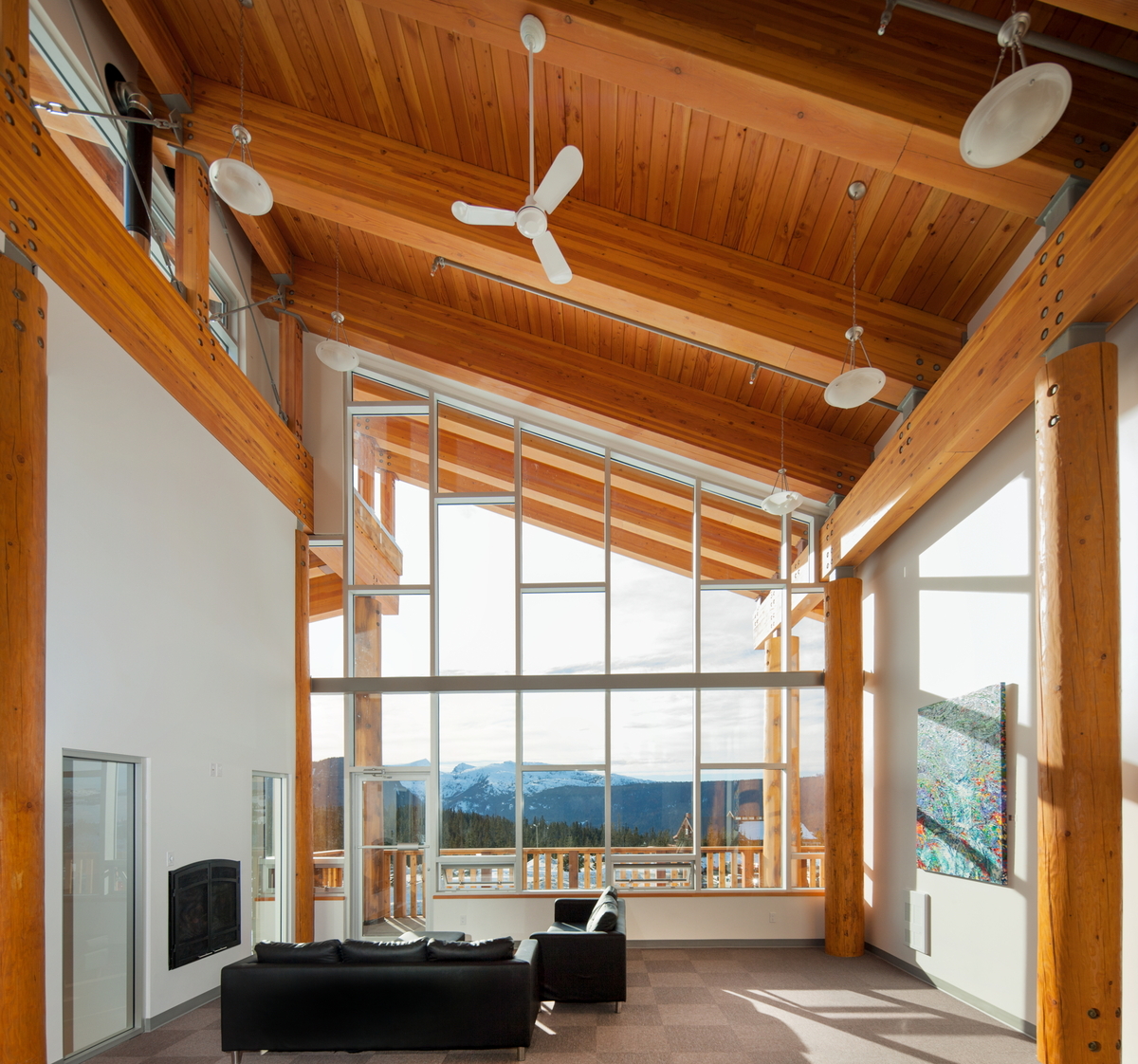 Interior sunny daytime image of the Vancouver Island Mountain Centre atrium, showing glue-laminated timber (Glulam) beams, and round solid-sawn heavy timber columns supporting a tongue and groove plank ceiling