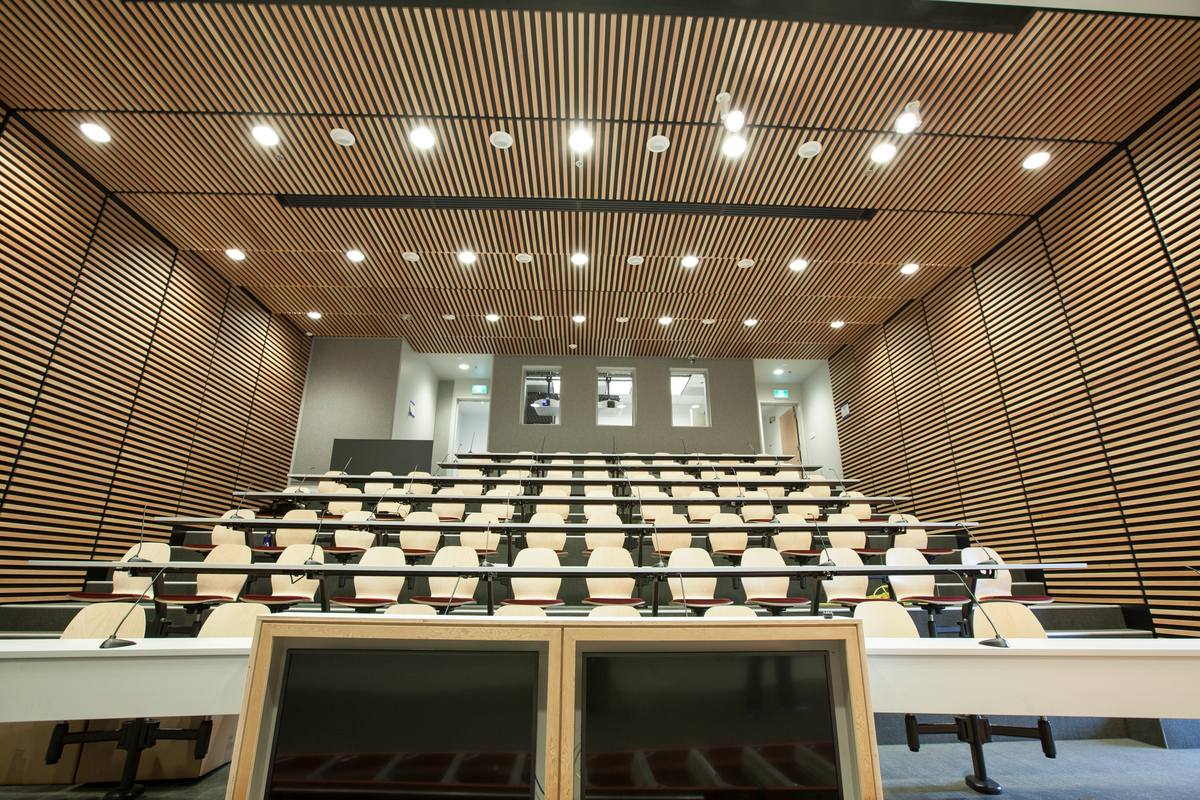 Decorative lumber slats are shown on both the walls and ceiling of this view of the main lecture hall of the Wood Innovation and Design Centre, as seen here from the lectern