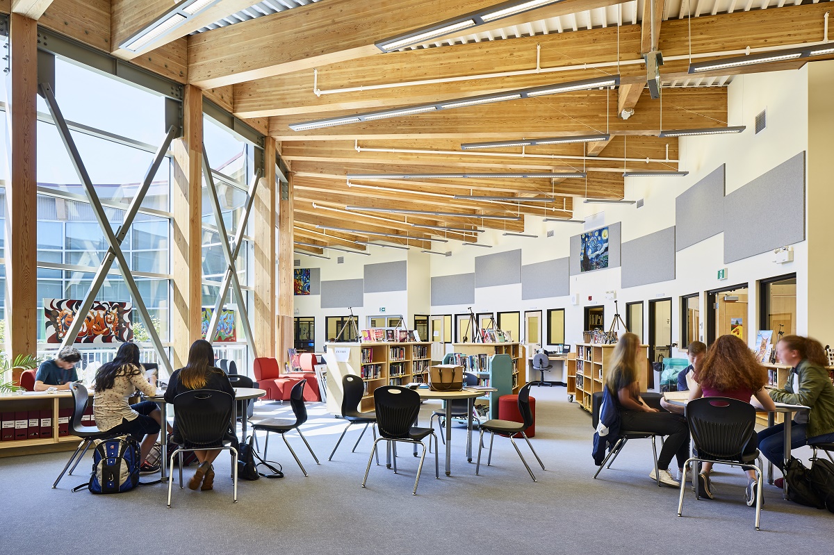 Internal daytime view of low rise Wellington Secondary School showing circular open library and research area with students at desks and Glue-laminated timber (Glulam) 