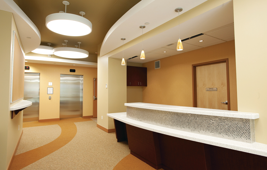 Wood trim, door, and accents are shown in this interior image of a reception area, including drop lighting, mirror ball tiled reception counter, and natural toned carpeting