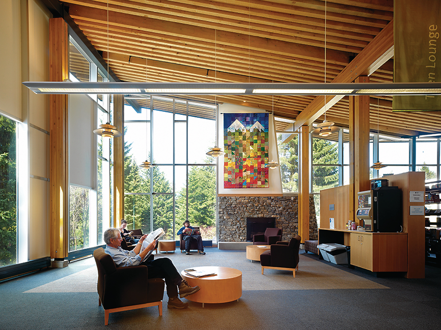 Interior sunny daytime view of occupied Whistler Public Library showing reclaimed Douglas fir millwork and featuring timber post & beam, passive house / high efficiency, and wooden prefabrication construction techniques