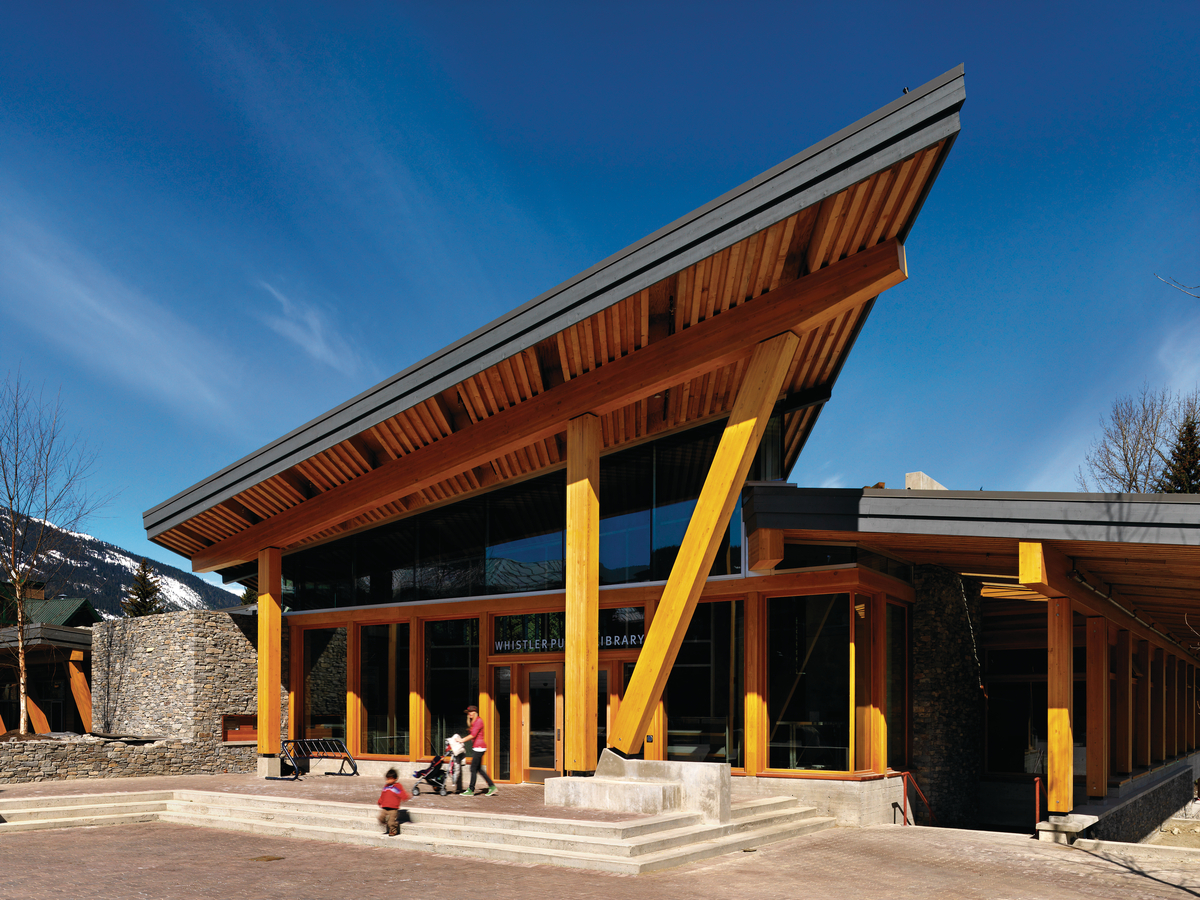 Exterior sunny daytime view of Whistler Public Library covered main entrance showing glue-laminated timber (Glulam), Millwork, trim, and exterior roof with slat on edge soffits