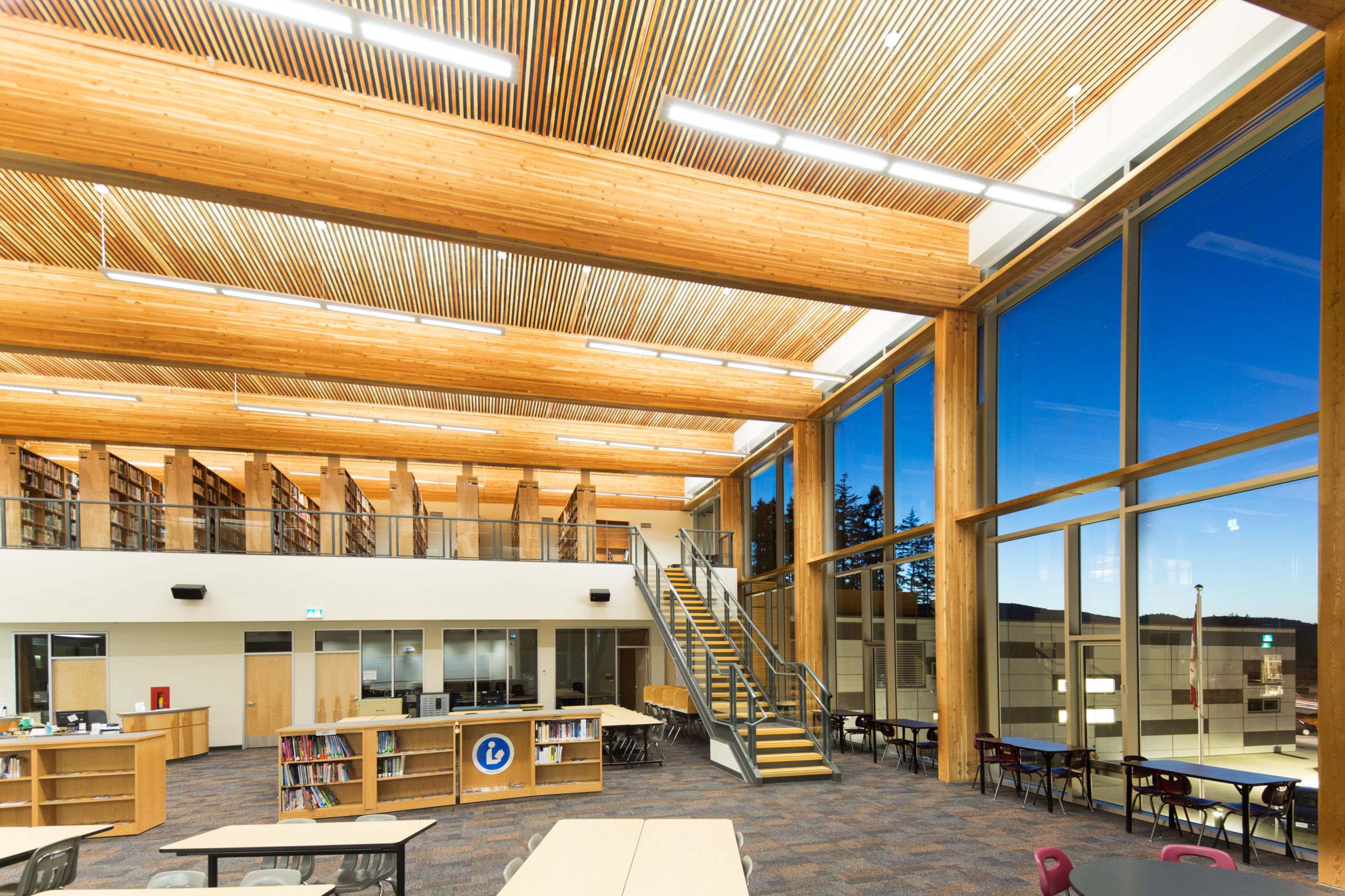 Wood book cases, desktops, staircase and hybrid ceiling construction feature prominently in this interior view of the Belmont Secondary School library.