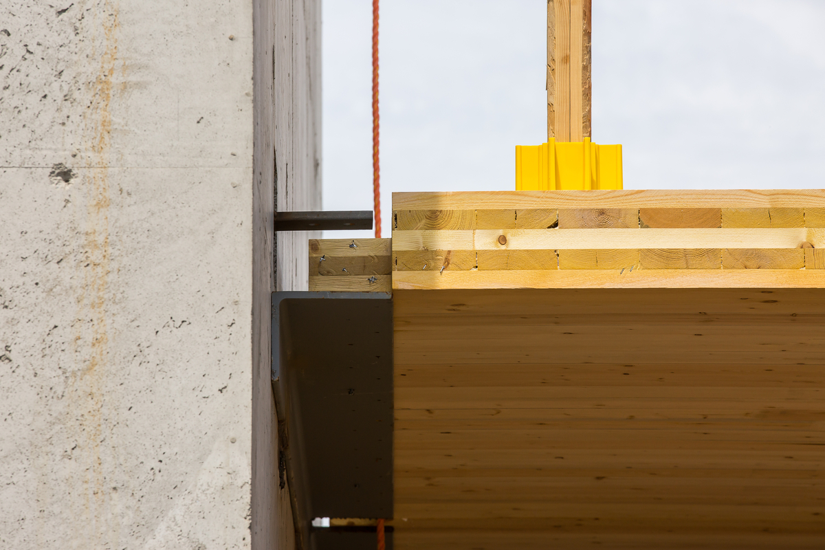 Outdoor close up view of cross-laminated timber (CLT) and concrete steel building connection