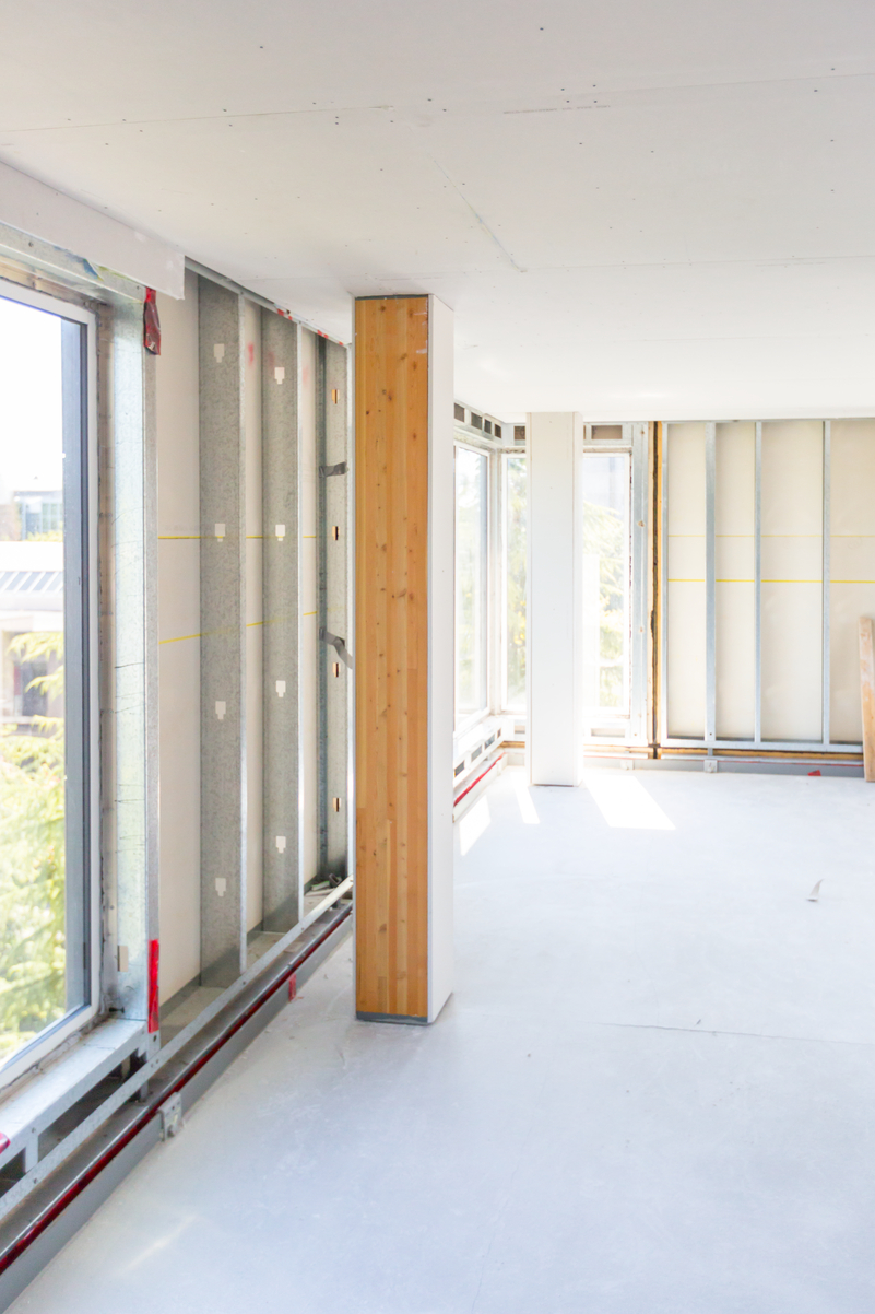 Interior daytime view of CLT panel (cross laminated timber) installation process, showing gypsum encapsulation within Brock Commons Tallwood House on the UBC Campus