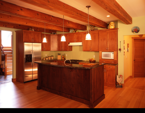 Interior daytime view of kitchen showing red alder (Alnus rubra) cabinets and ceiling beams