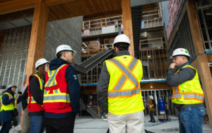 Building professionals in high-reflective vests tour a mass timber construction site.