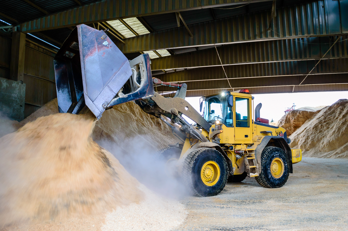 Daytime image of residual wood fiber being moved by commercial front loader. Residuals are the starting point for wood pellets, which are biofuels made from compressed wood fibre
